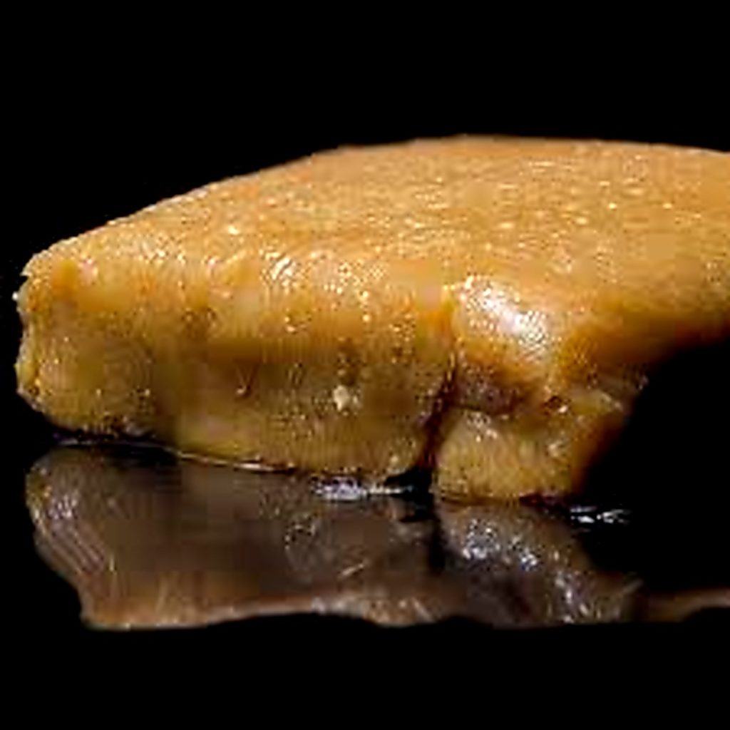 Bloc de résine de cannabis concentrée riche en trichomes montrant la texture caractéristique du hash obtenu à partir des glandes résineuses de la plante.